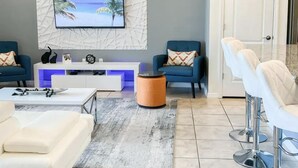 Ein modernes Wohnzimmer mit Flachbildfernseher, Deckenventilator und einer Wandtafel mit der Aufschrift 'Eat'.