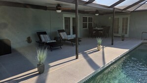 A covered patio area with a pool, lounge chairs, and a dining table. - Butterfly House, close to beaches, restaurants, live entertainment & shopping (Sarasota)