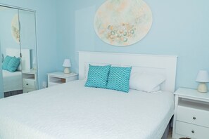 Une chambre à coucher comprenant un lit, deux tables de chevet, une commode, un miroir et une œuvre d’art murale.