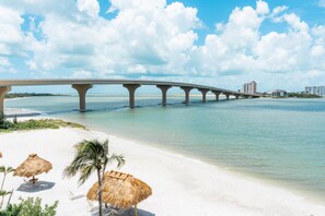 A coastal bridge with a beach in the foreground.