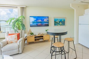A living room with a sofa, a coffee table, two bar stools, a small wooden cabinet, and two paintings on the wall. - #301 Ocean View at Lovers Key Beach Club (Bonita Springs)