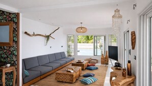 Een moderne woonkamer met een grijze bank, een houten salontafel en een grote televisie.