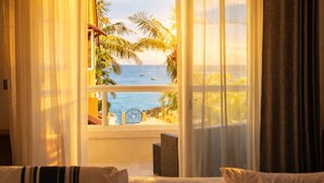 Een kamer met uitzicht op zee, een balkon en een rieten stoel.