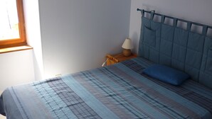 Ein Schlafzimmer mit einem Bett, einem Nachttisch, einer Lampe und einem Fenster.