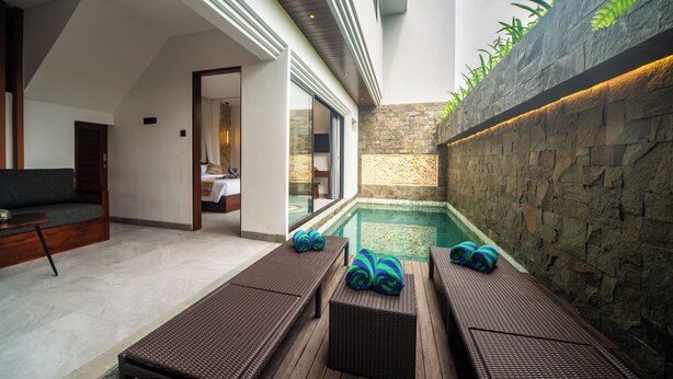 A modern outdoor spa area with a stone wall, a pool, and lounge chairs with towels. - 3Bedroom-703-Private Pool Villa Sanur (Denpasar)