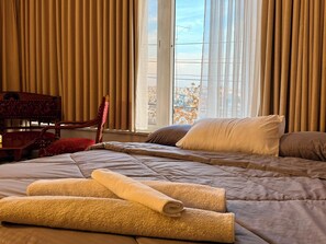 Ein Hotelzimmer mit Bett, Stuhl und einem Fenster mit Vorhängen.