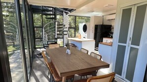 A modern kitchen with a built-in oven and a dining area with a wooden table and chairs. - Hacker House - Do Your Best Work (LaGrange)