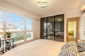 Un dormitorio amplio con una cama grande, un balcón con mesa y sillas, y vistas al exterior.
