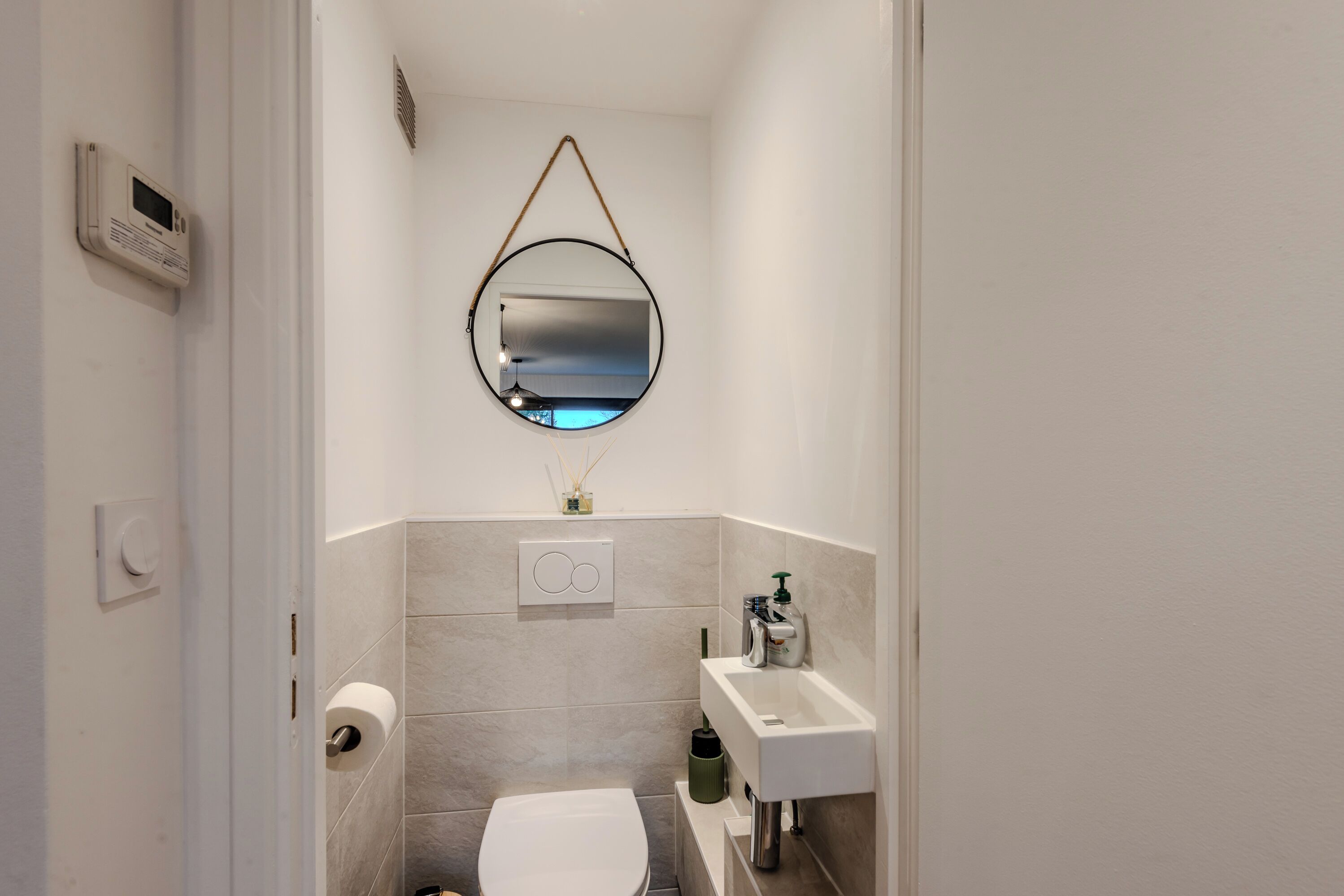 A compact bathroom with a toilet, a sink, and a mirror.