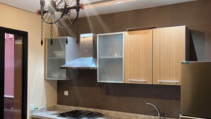 Une cuisine moderne équipée d’un réfrigérateur en acier inoxydable, d’une cuisinière à gaz, d’un évier et de meubles de rangement en bois.