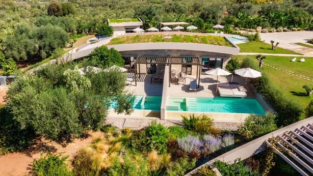 Eine moderne Villa mit Pool, Sitzgelegenheiten im Freien und üppiger Bepflanzung.