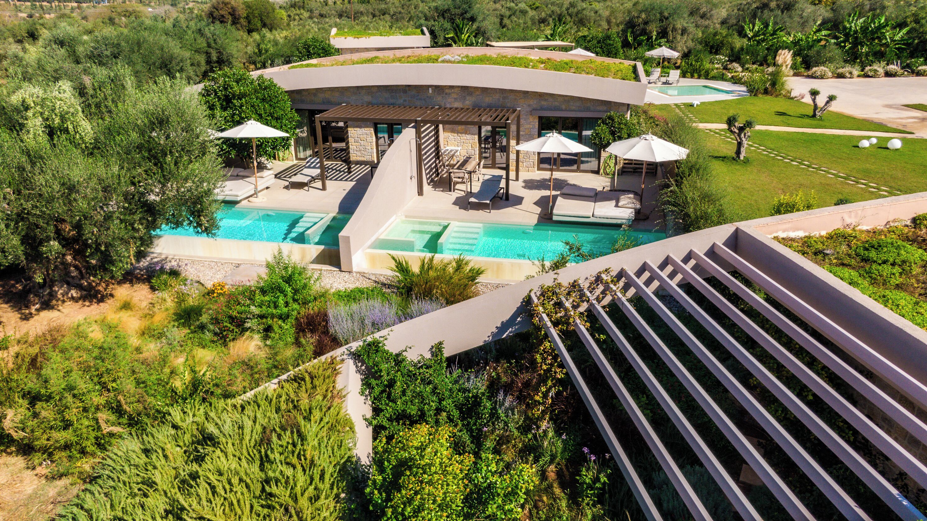 A modern resort with a pool, lounge chairs, and a covered patio area.