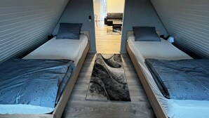 A modern, compact room with two single beds, a central rug, and a view into an adjacent living area. - Sønderborg in Denmark (Sønderborg)