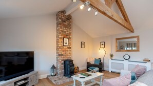 A cozy living room with a TV, fireplace, and comfortable seating. - The Garden House in Low Catton (York)