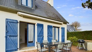 A house with a patio, a table with chairs, and a barbecue grill. - Large family home 10 minutes from the beach (Fouesnant)