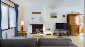 A living room with a fireplace, a television, and a wooden cabinet. - Large family home 10 minutes from the beach (Fouesnant)