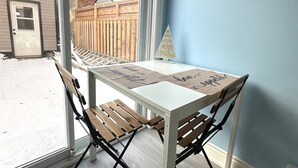 Ein Zimmer mit Tisch, Stühlen, einem Fenster und Blick auf einen Hinterhof.