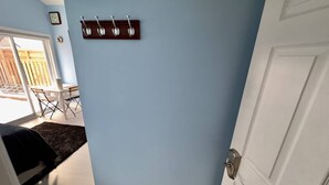Ein Zimmer mit blauer Wand, einem Holzmantelständer, einer weißen Tür und Blick auf eine Außenpatio.