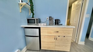 Eine kompakte Küchenzeile mit Mikrowelle, Kaffeemaschine und kleinem Kühlschrank.