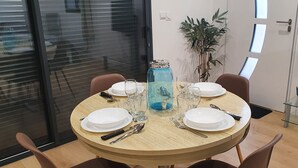Une table à manger dressée avec des assiettes, des couverts et un bocal en verre bleu.