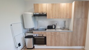 Une cuisine compacte avec des meubles en bois, un four encastré, un évier et un chauffe-eau.