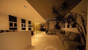 A modern interior with a reception desk, a curved sofa, and a large plant. - Las Mariposas 22-2F (Santo Domingo)