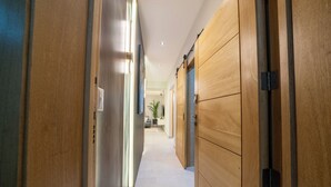 A hallway with wooden doors and a tiled floor. - Las Mariposas 22-2F (Santo Domingo)