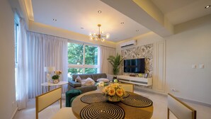 A modern living room with a sofa, TV, and a dining area with a round table and chairs. - Las Mariposas 22-2F (Santo Domingo)