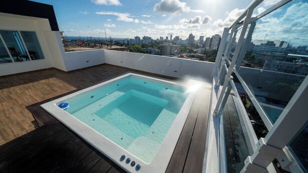 A rooftop swimming pool with a city view, surrounded by a modern building with large windows. - Las Mariposas 22-2F (Santo Domingo)