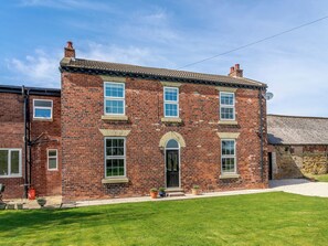 A two-story brick house with a symmetrical facade, a central arched doorway, and multiple windows.
