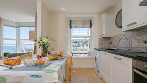 Una cucina moderna con zona pranzo, ampie finestre e vista mare.