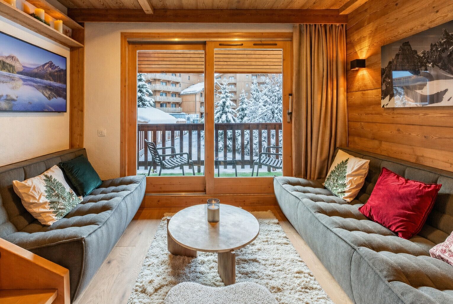Ein gemütliches Zimmer mit zwei Sofas, einem runden Couchtisch und Blick auf einen verschneiten Balkon.