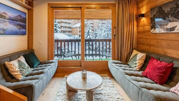A cozy room with two sofas, a round coffee table, and a view of a snowy balcony.