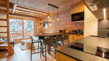 A modern kitchen with wooden accents, a bar area, and a view of snow-covered trees.