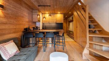 A cozy cabin interior with a wooden interior, a sofa, a dining area, and a staircase.