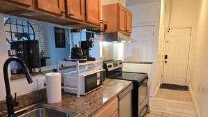 A kitchen with granite countertops, stainless steel appliances, wooden cabinets, and a black dishwasher.