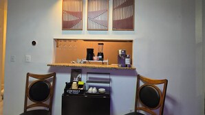 A compact bar area with a coffee station, two chairs, and decorative wall panels.