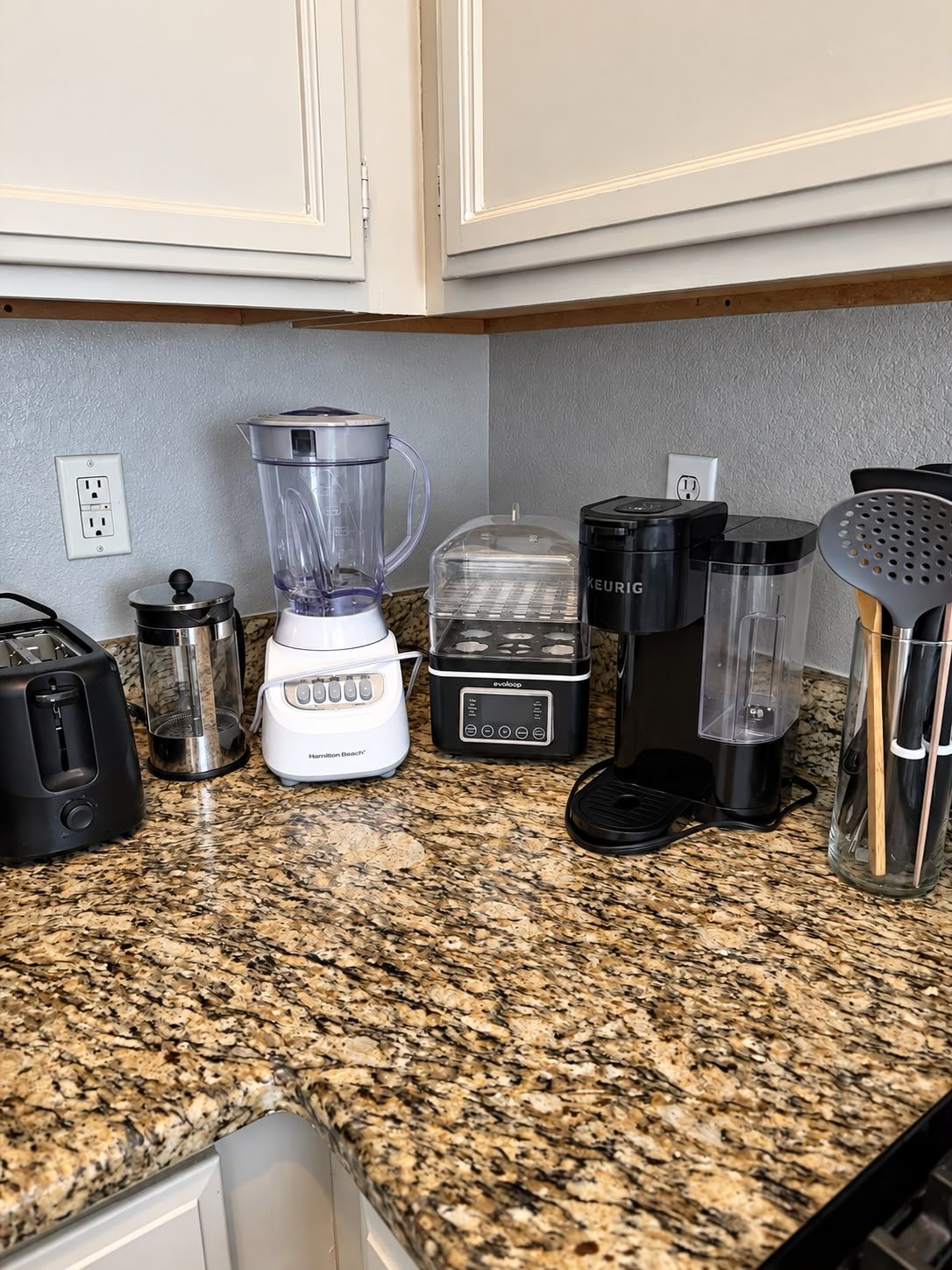 Eine Küchenarbeitsplatte mit Mixer, Toaster, Kaffeemaschine und weiteren Geräten.