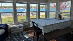A room with a large table, a bench, and a view of a lake.