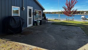 A small dock with a covered area, a grill, and a view of a lake with boats.