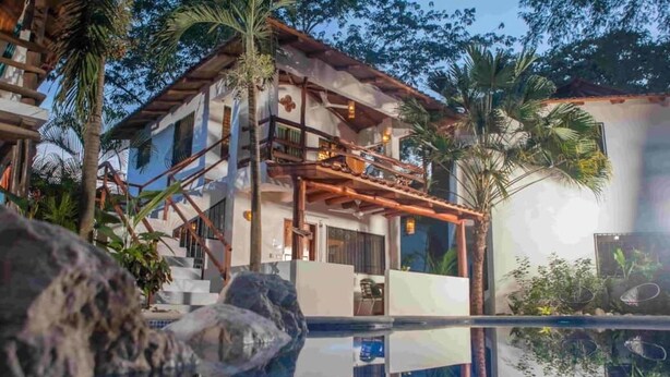 A multi-story building with a wooden staircase, outdoor seating, and a pool area.