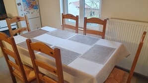 A dining table with a white tablecloth and four wooden chairs with woven seats. - Quiet house close to all amenities and train station (Chauffailles)