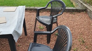A patio area with two black plastic chairs and a table covered with a white tablecloth. - Quiet house close to all amenities and train station (Chauffailles)