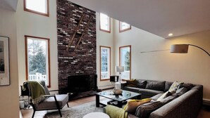A modern living room with a fireplace, large windows, and a cozy seating area.