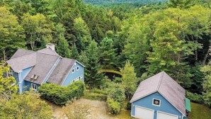 A residential area with two houses surrounded by dense forest.
