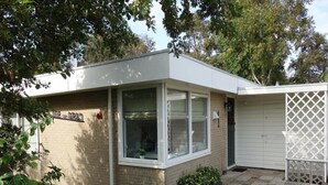A single-story house with a brick exterior, a front porch, and a small garden area. - Bungalow in Sint Maartenszee Near Beach (Sint Maartensvlotbrug)