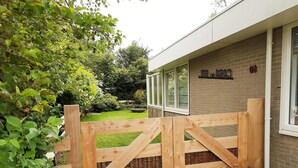 A wooden gate leading to a building with a brick facade and a window with the number 30. - Bungalow in Sint Maartenszee Near Beach (Sint Maartensvlotbrug)