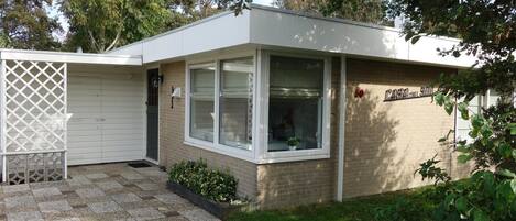 A single-story building with a garage door, a small front porch, and a brick exterior.