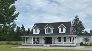 A two-story house with a front porch, a brick chimney, and a flag.