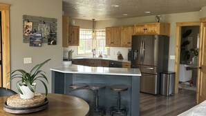 A modern kitchen with wooden cabinets, a stainless steel refrigerator, and a central island with stools.